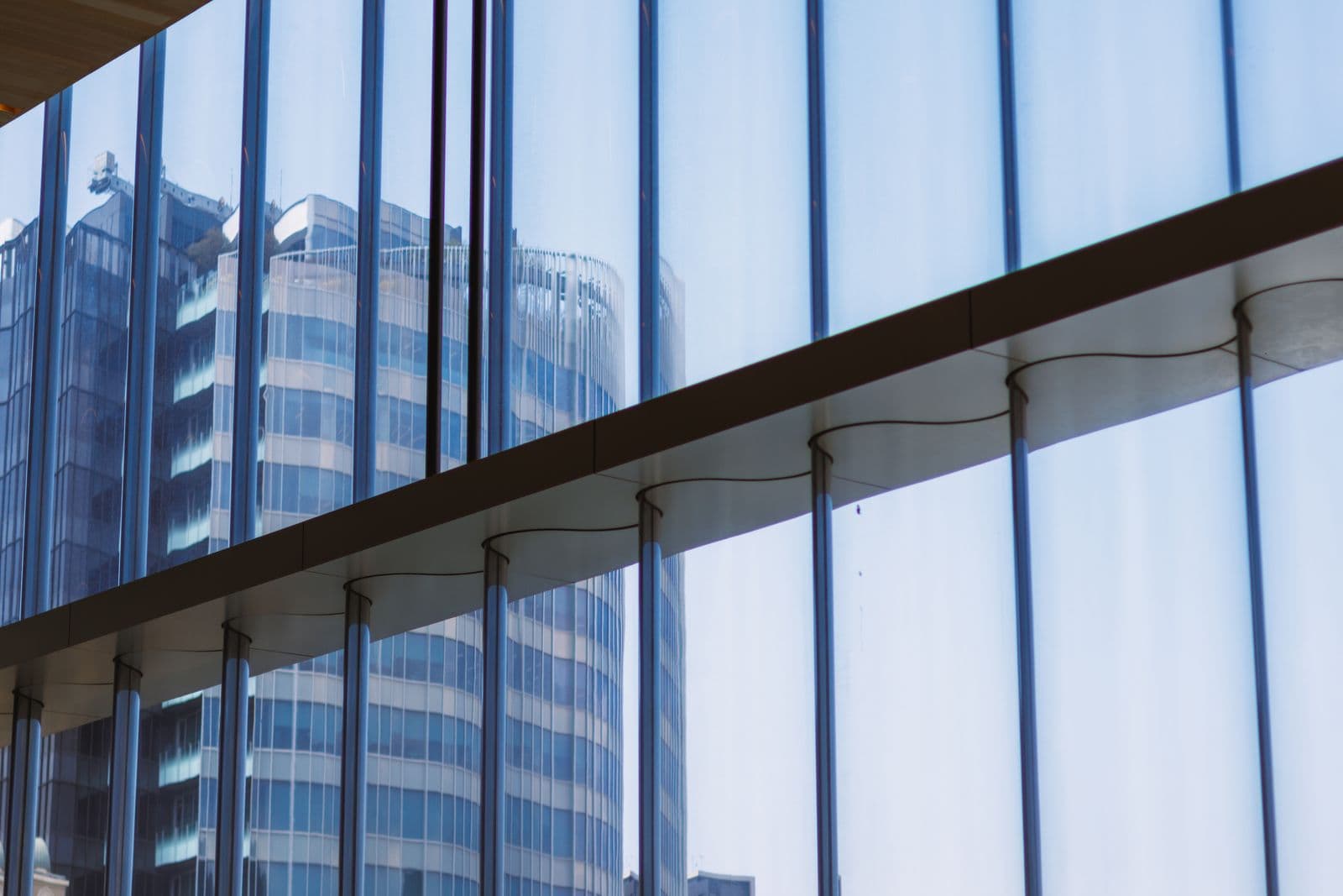 Reflet de bâtiments modernes dans une façade vitrée bleue