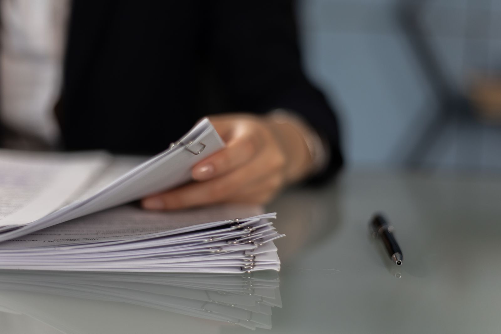 A person sorting a stack of documents at a desk.